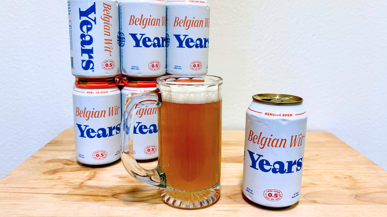 Une chope de Years Belgian Wit à côté de sa canette, avec d'autres canettes en arrière-plan