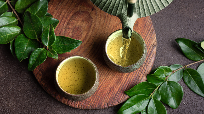 Verser du thé vert dans deux tasses.