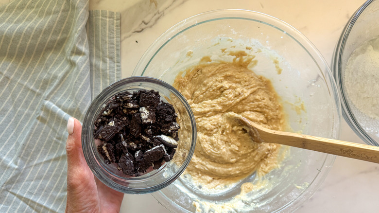 main ajoutant des oreos au bol