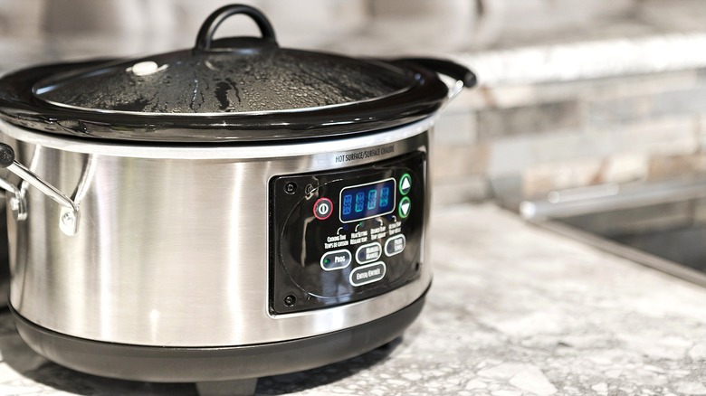 Mijoteuse argentée et noire réglée au minimum sur un comptoir gris marbre