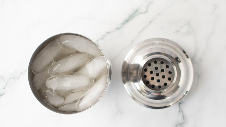 Shaker plein de glace et de liquides à côté du couvercle