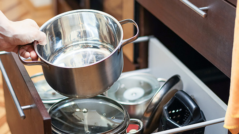 personne tenant un pot brillant dans une armoire de cuisine