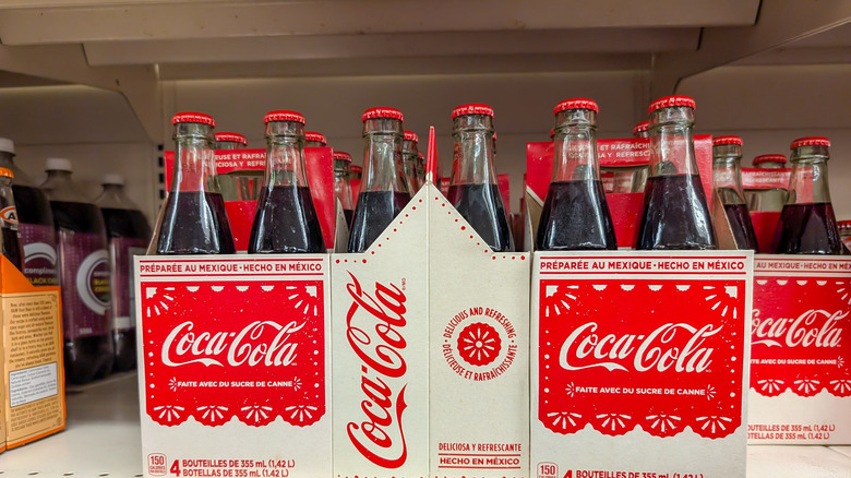 Bouteilles en verre de Coca mexicain dans des cartons sur les étagères des magasins.