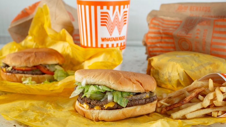 Une exposition d'articles de Whataburger, notamment deux hamburgers non emballés, un article emballé, une boisson et des frites