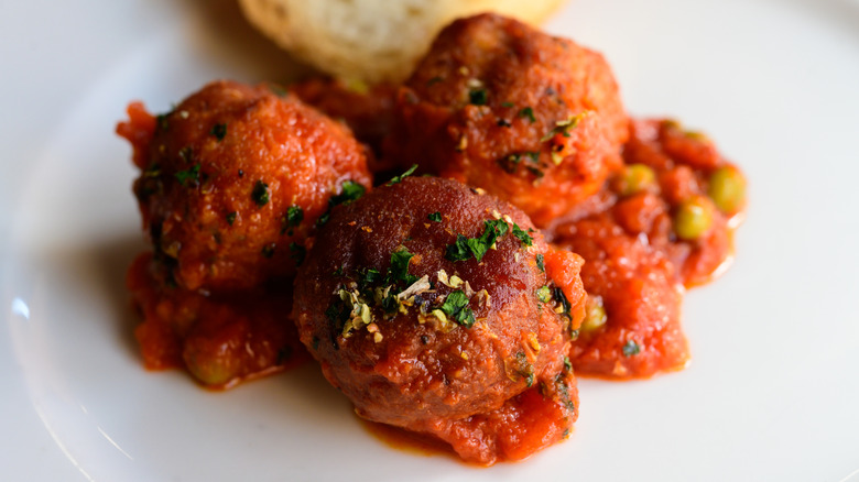 Boulettes de viande italiennes avec sauce sur une assiette blanche.