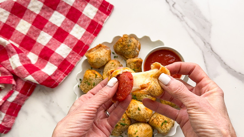 mains séparant une bouchée de pizza