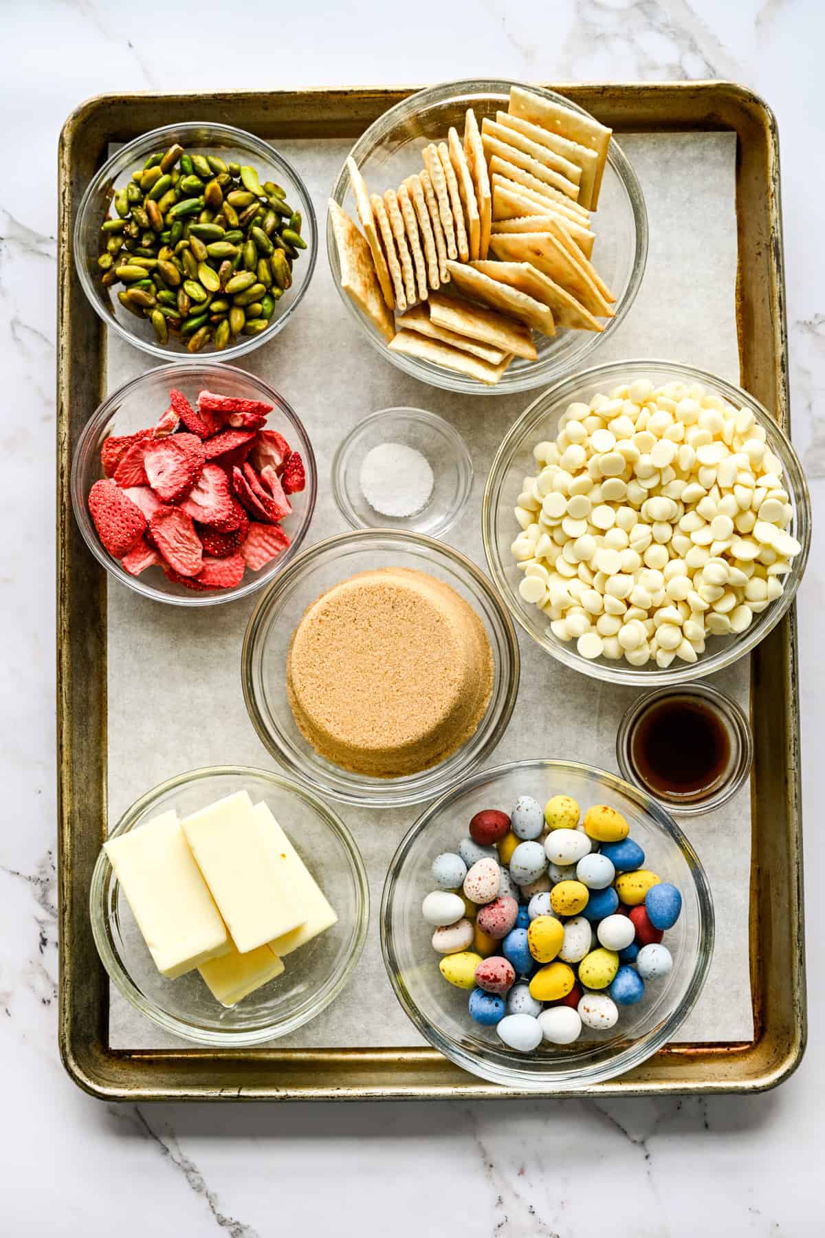 Vue aérienne des ingrédients du crack de Pâques, notamment les pépites de chocolat blanc, le beurre et le sucre.