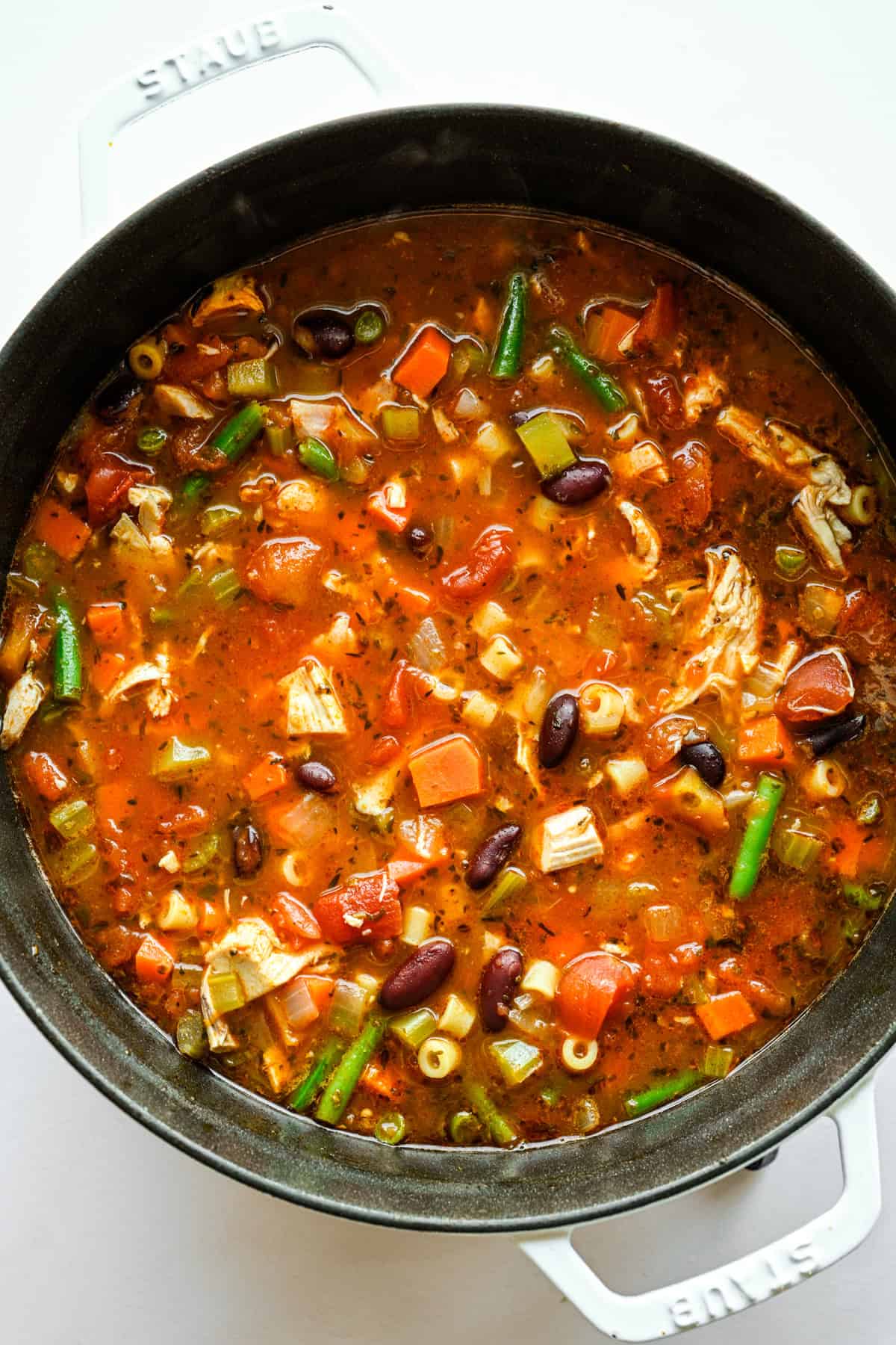 Pâtes, haricots verts et poulet mijotés dans la marmite avec le reste des ingrédients.