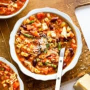 Soupe minestrone au poulet dans un bol blanc avec une cuillère.