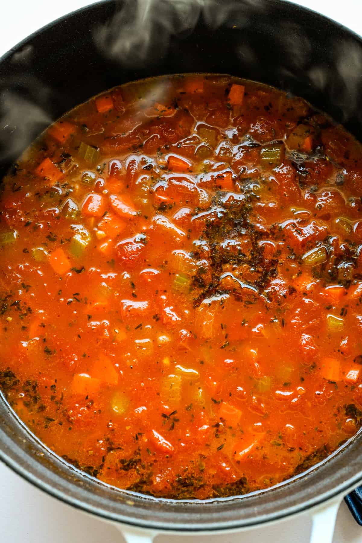 Bouillon et tomates ajoutés à la marmite.