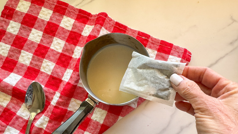 main ajoutant un sachet de thé