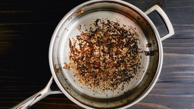 Restes de nourriture collés au fond d'une casserole en acier inoxydable qui doit être déglacée.