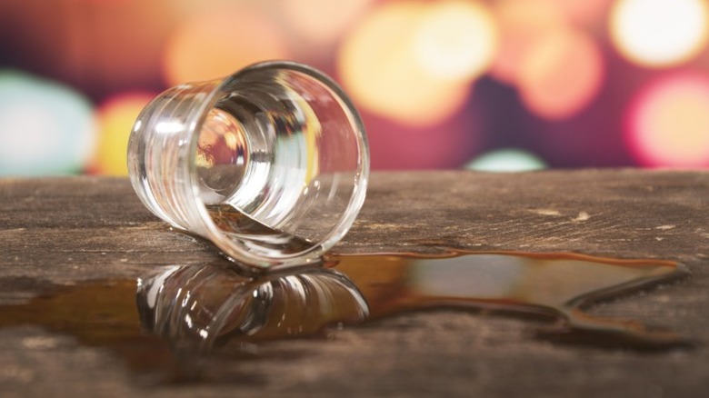 Un verre de whisky renversé sur une surface en bois.