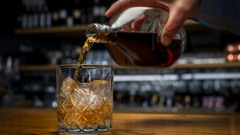 Un individu verse du scotch dans un verre.