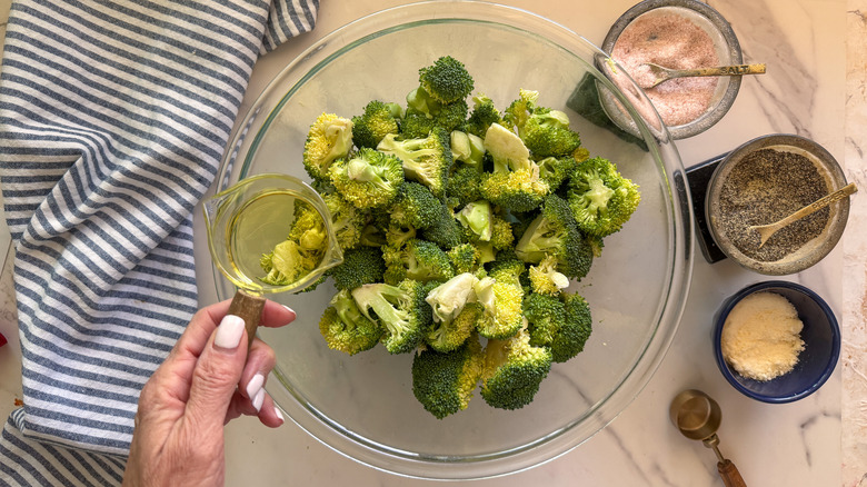 main, ajouter de l'huile dans un bol avec du brocoli