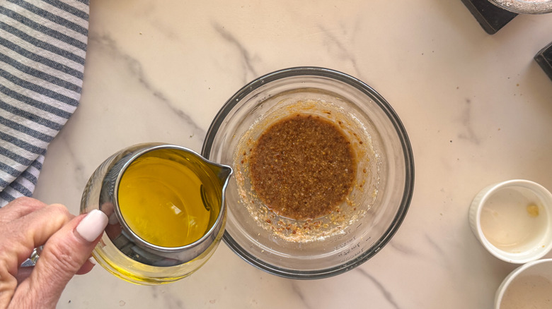 main, ajout d'huile d'olive dans un bol