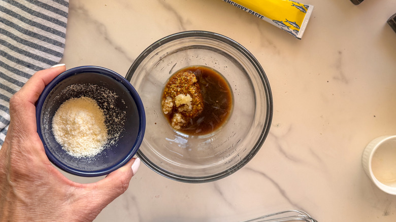 main ajoutant du parmesan au bol