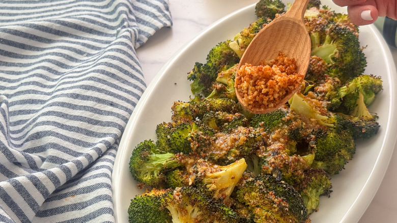main ajoutant du panko au brocoli