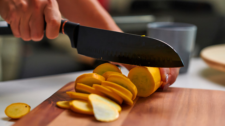 trancher une courge avec un couteau sur une planche à découper en bois