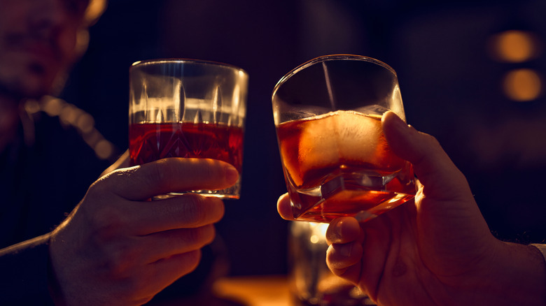 Mains tenant des verres de bourbon