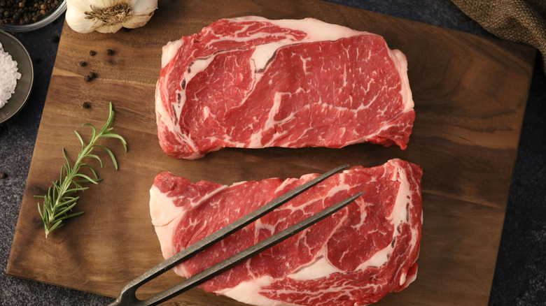 deux steaks de faux-filet sur une planche à découper en bois