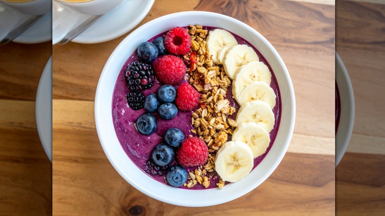 Bol d'açaí garni de myrtilles, de mûres, de framboises, de granola et de tranches de banane