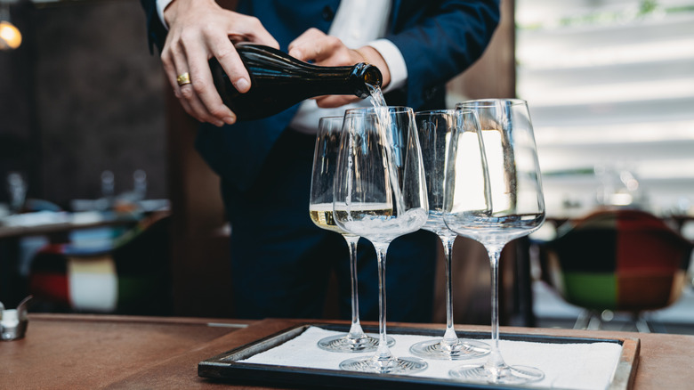 Un serveur versant du Prosecco dans des verres dans un bel établissement