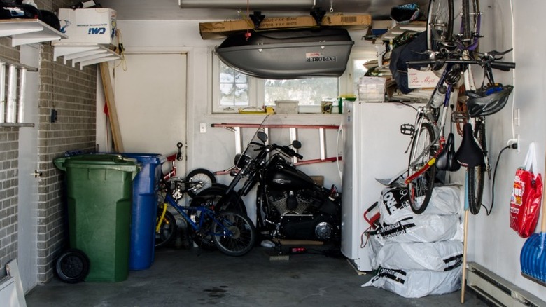 Un réfrigérateur dans un garage entouré d'objets extérieurs.