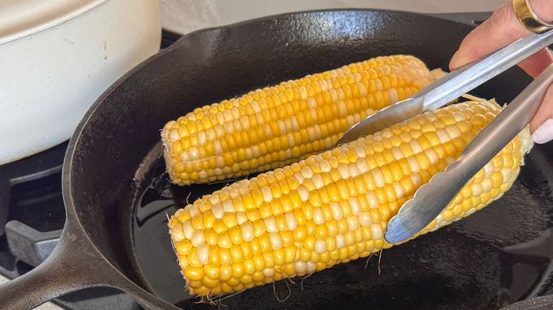 main ajoutant du maïs à la poêle