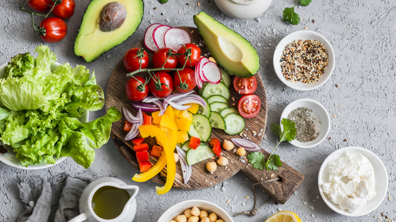 Plusieurs variétés de produits comme les tomates, les concombres et les avocats sont disposées sur un plateau.