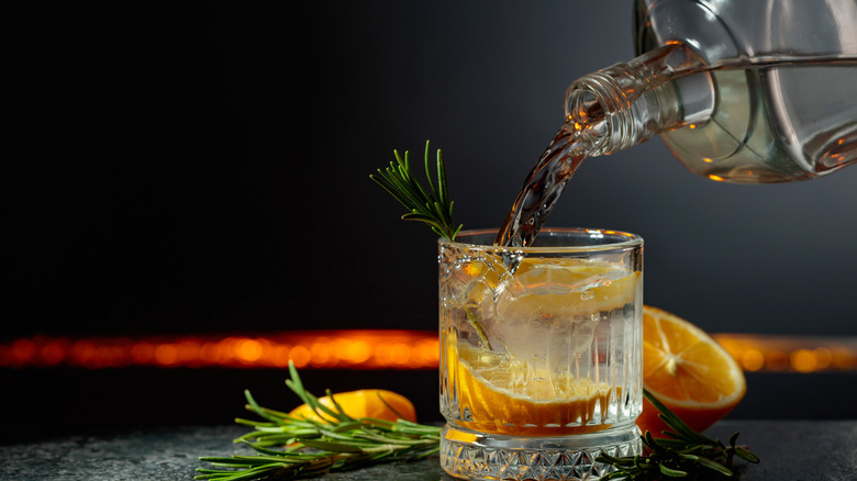 Gin étant versé d'une bouteille dans un verre pour un cocktail gin tonic