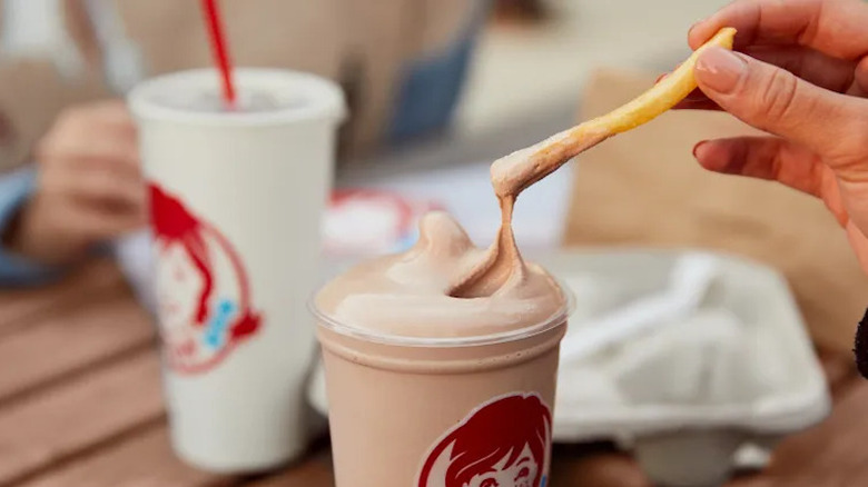 Une personne trempant une frite dans un Wendy's Frosty