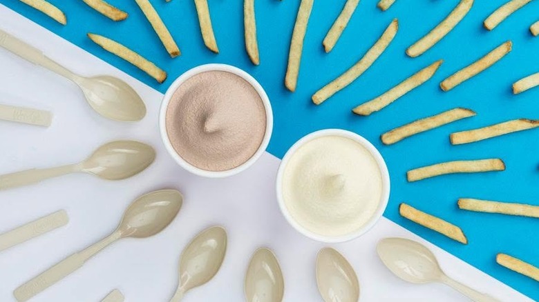Un Chocolate Frosty et Vanilla Frosty de Wendy's sur une table avec des cuillères et des frites