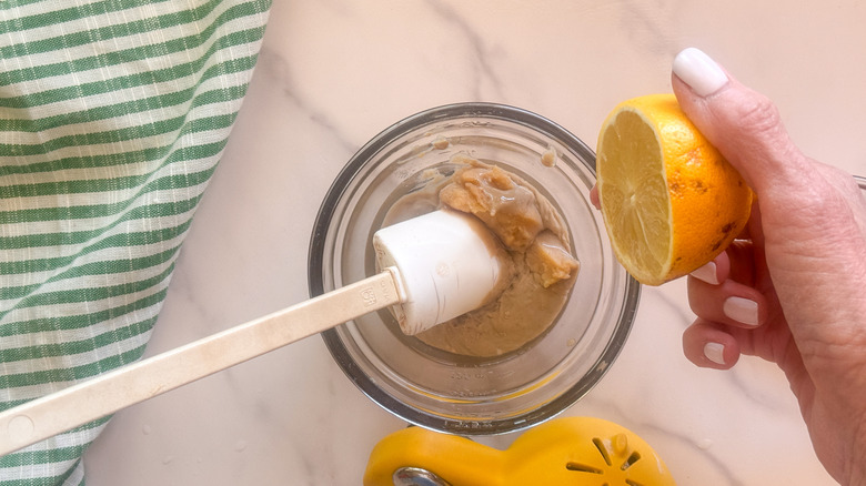 main pressant le citron dans la sauce