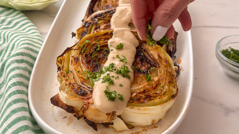 saupoudrer à la main du persil sur du chou rôti avec de la sauce tahini