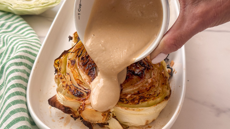 verser à la main un filet de sauce tahini sur le chou