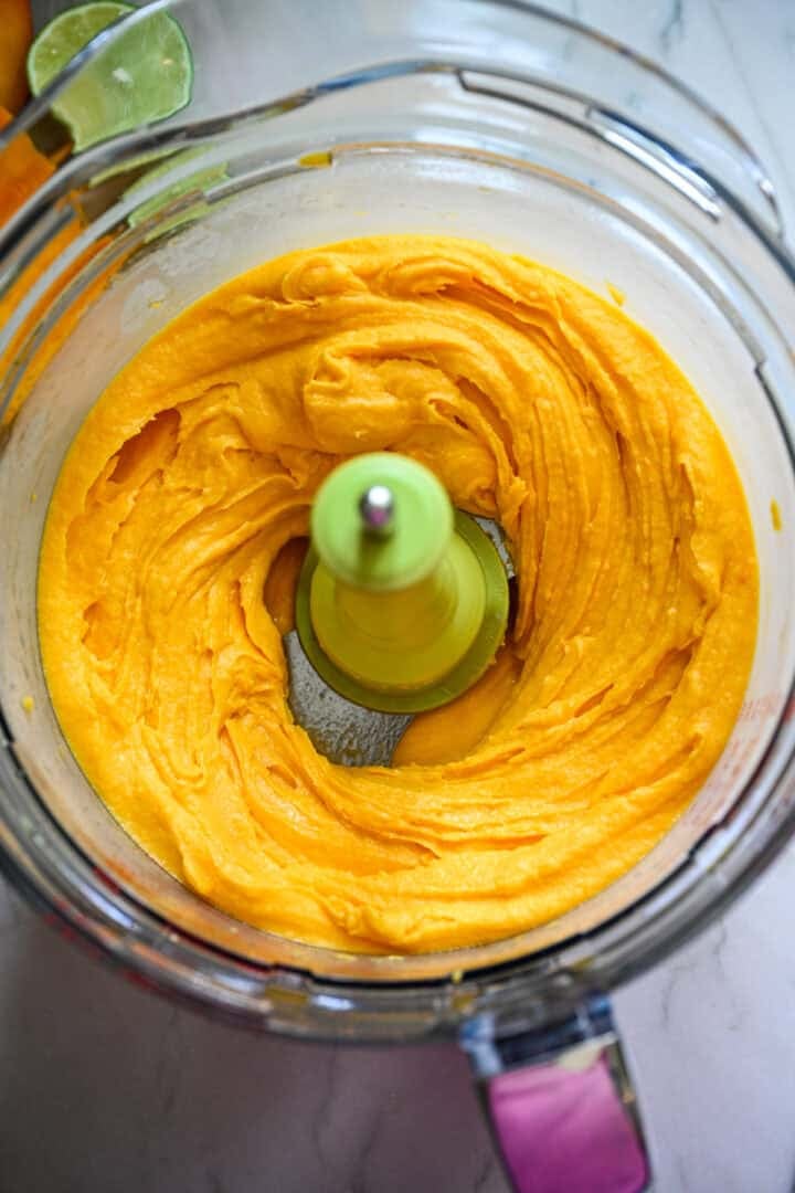 Ingrédients du sorbet à la mangue dans un robot culinaire après mélange.