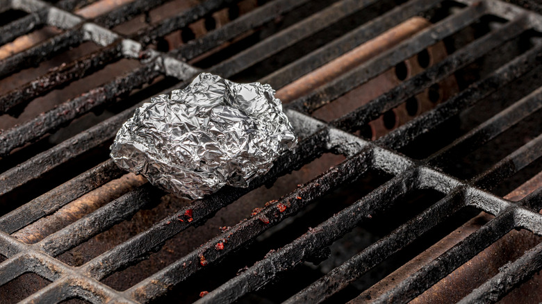 Boule de papier d'aluminium sur des grilles sales