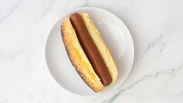 Hot dog dans un petit pain sur une assiette blanche
