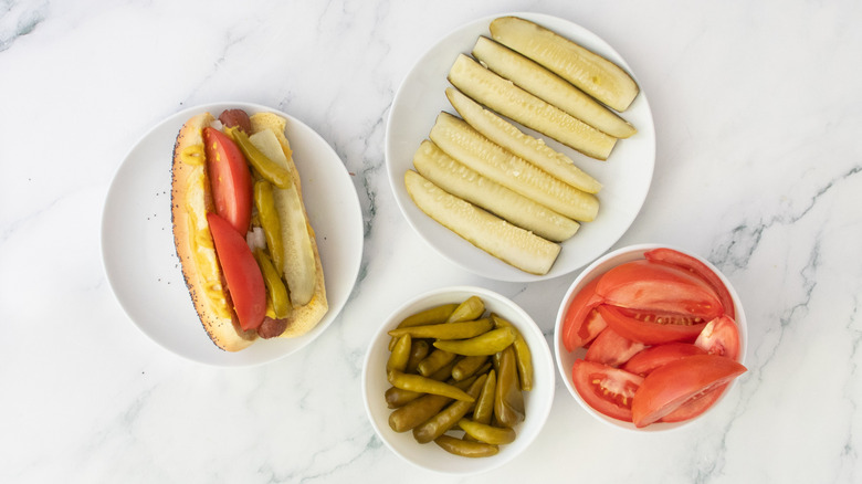 Hot-dog dans un petit pain garni d'oignons, de relish, de cornichons, de quartiers de tomates et de poivrons