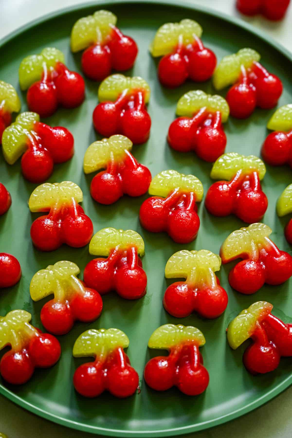 Vue aérienne de plusieurs bonbons aux cerises sur une assiette verte.