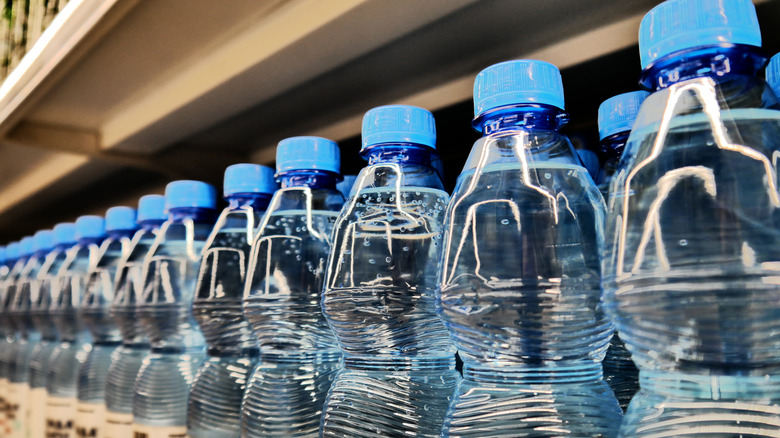 Bouteilles d'eau alignées dans un supermarché.