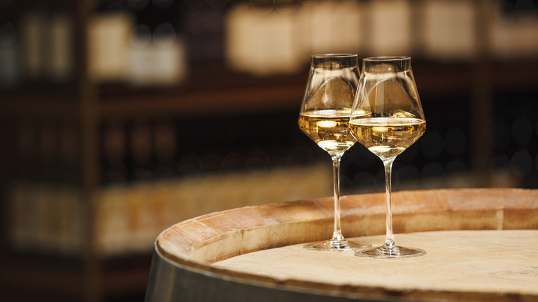 Deux verres de vin blanc sur un fût de chêne.