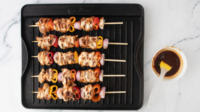 Grillés et brochettes sur une poêle à griller avec sauce barbecue à part