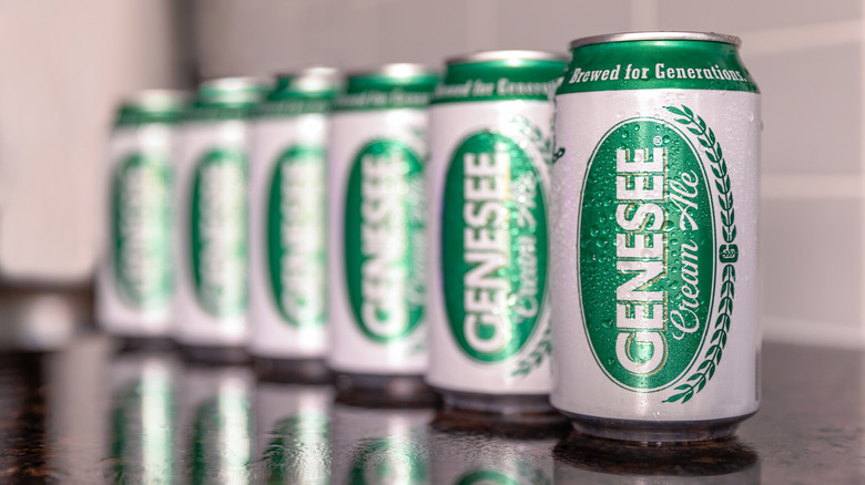 Six canettes de Genesee Cream Ale alignées sur une surface réfléchissante