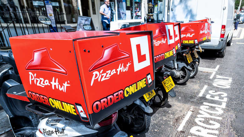 Des scooters de livraison Pizza Hut alignés dans une rue
