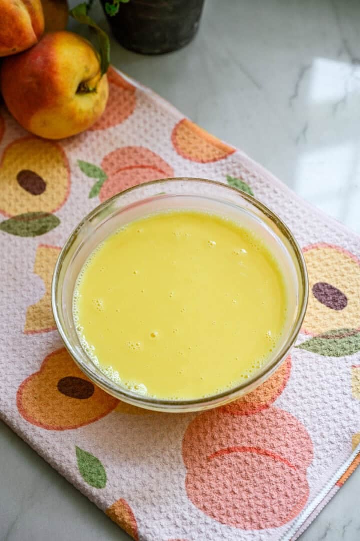 Vue aérienne des jaunes d'œufs et du lait tempéré dans un petit bol en verre.