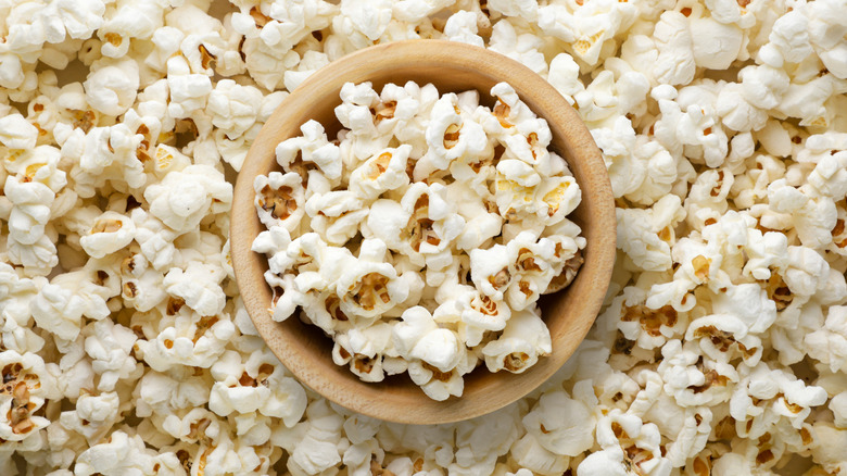 une vue de dessus d'un bol en bois de pop-corn sur un fond avec plus de pop-corn