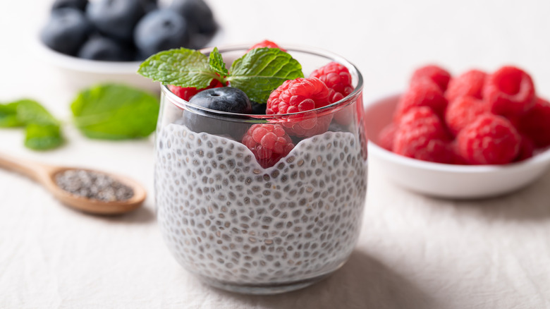 une tasse de pudding au chia garni de framboises, de myrtilles et de menthe