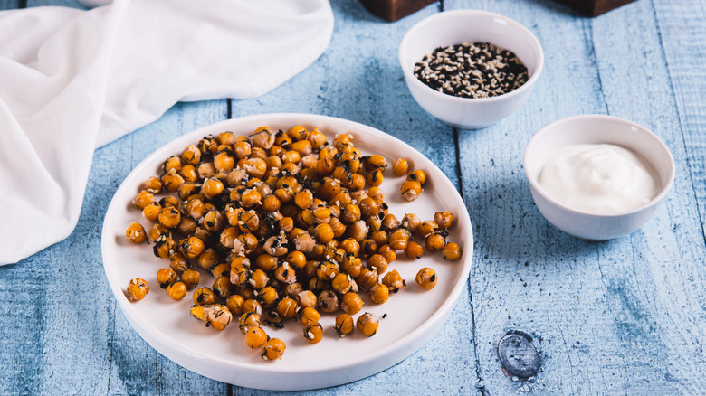 une assiette de pois chiches rôtis aux graines de sésame et aux herbes sur une table en bois